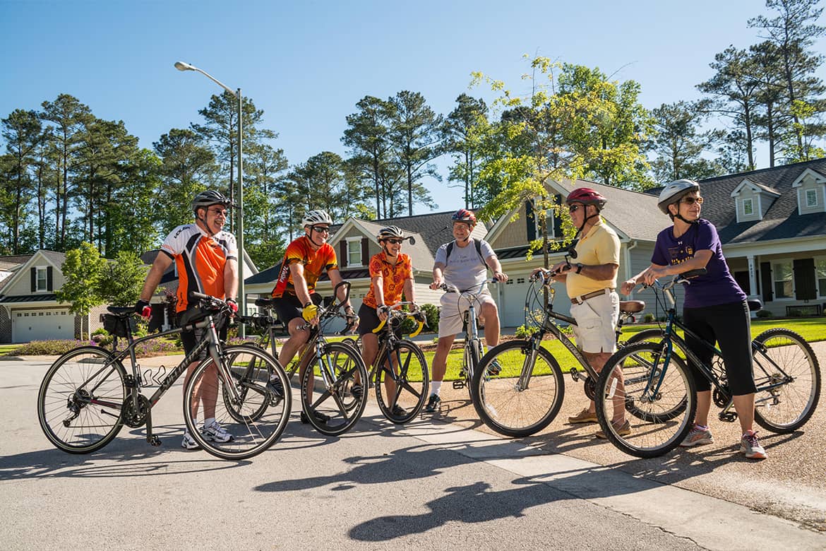 Members of Carolina Colours community bicycle club gather together in front of neighborhood homes